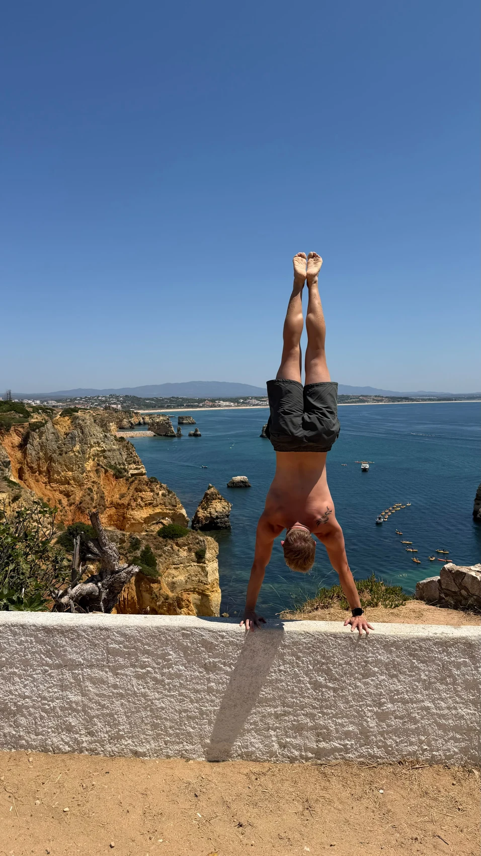 Fotografia di una verticale sulle mani con il mare sullo sfondo